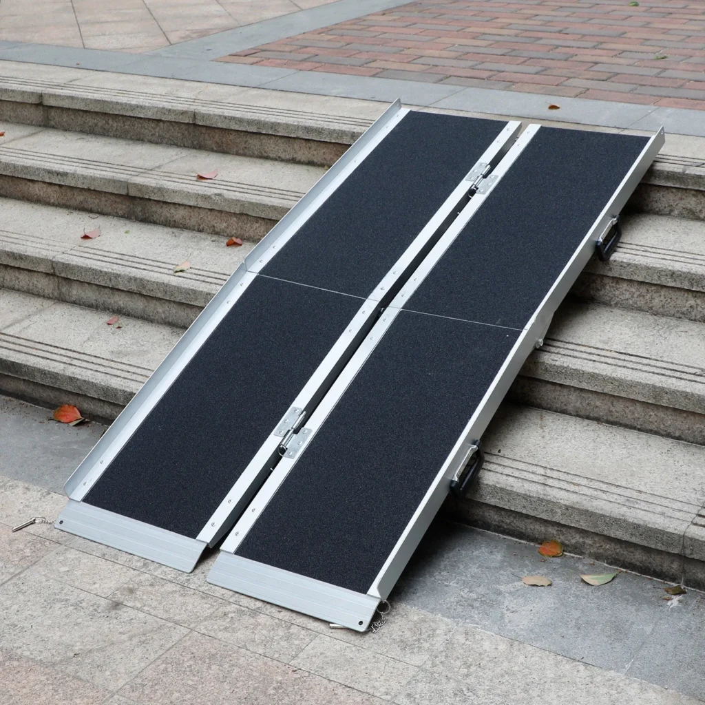 A foldable aluminium portable ramp leaning against steps